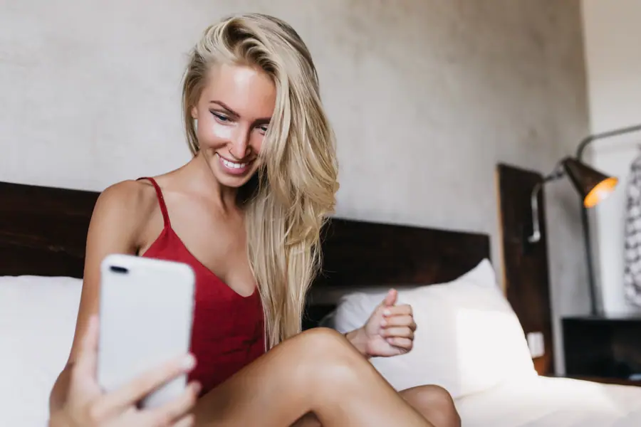 Femme blonde en camisole rouge au téléphone, rencontre sexe à Rimouski